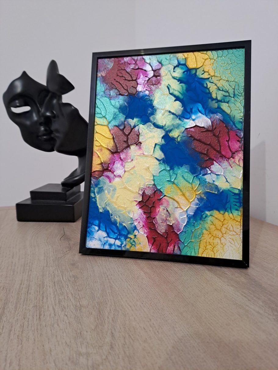 "Rêve pigmenté" Peinture abstraite colorée avec des motifs en rouge, bleu, jaune et vert, près d'une sculpture.