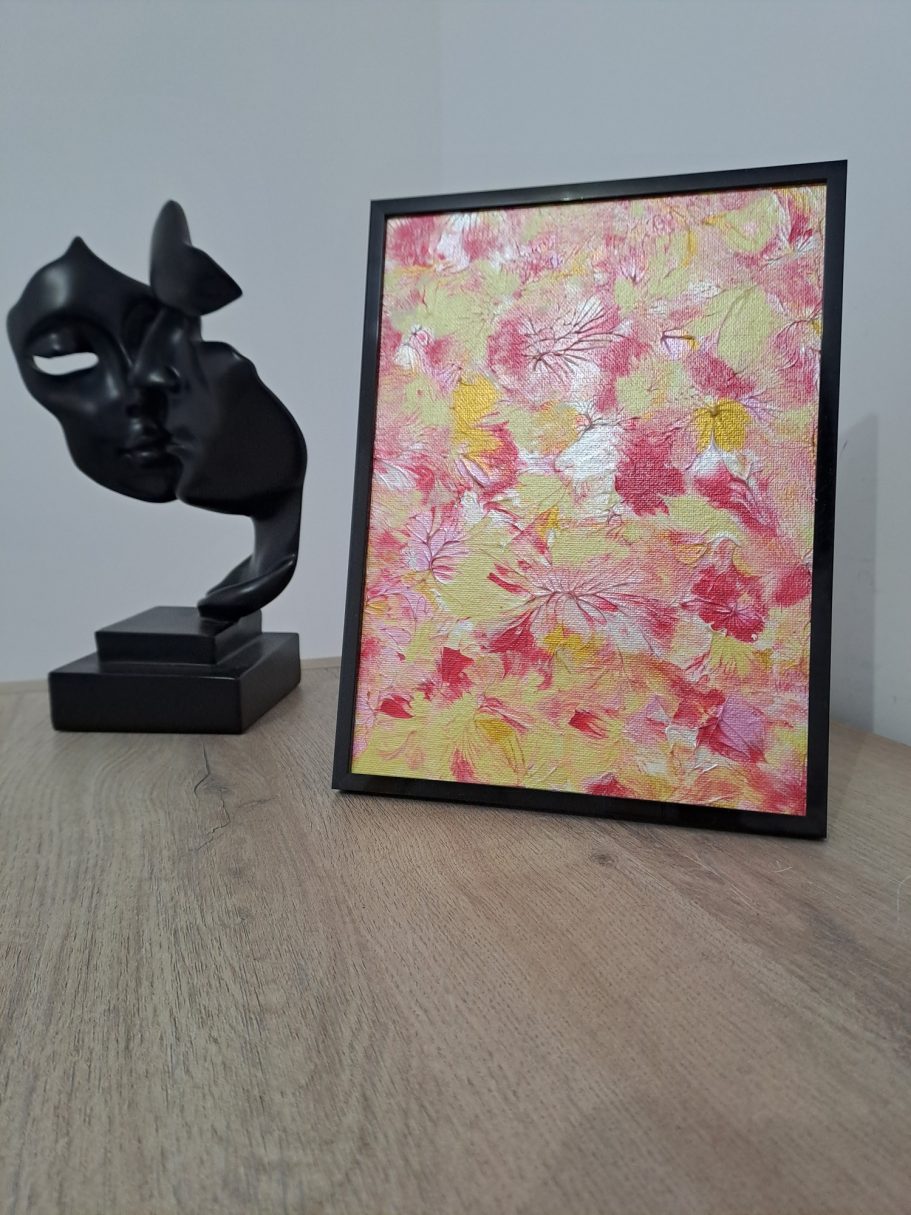 "Feu de pétales jaunes" Cadre avec une œuvre abstraite colorée et une sculpture noire sur une table en bois.