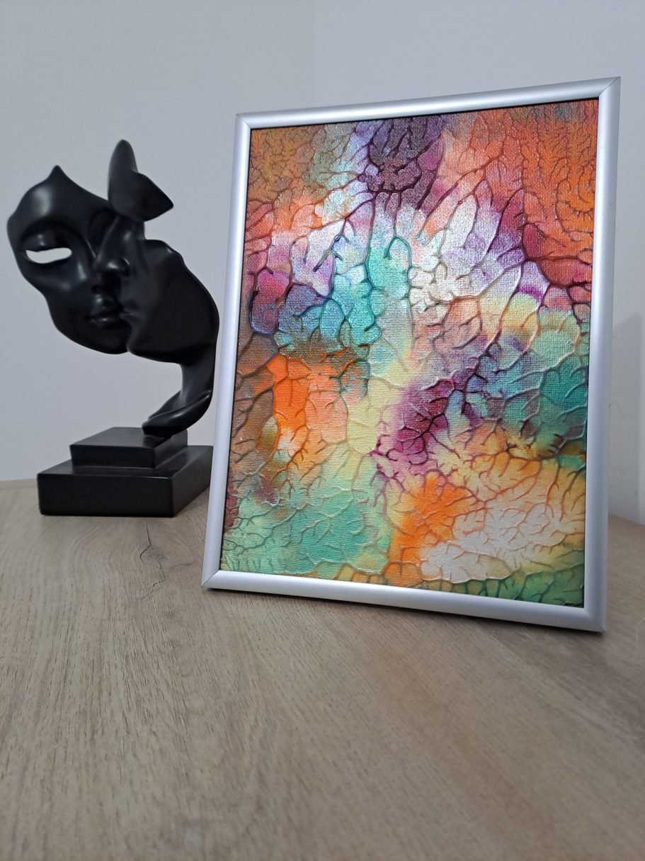 " Terre et lumière" Une sculpture noire stylisée à côté d'une œuvre colorée encadrée sur un meuble en bois.