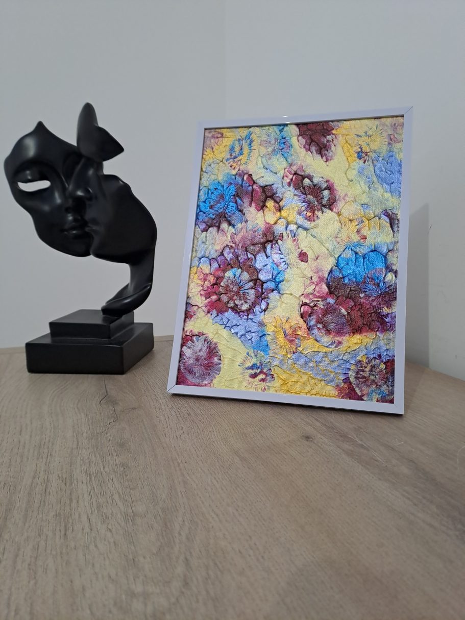 "Éclosion chromatique" Une sculpture noire à côté d'une illustration colorée sur une table en bois.