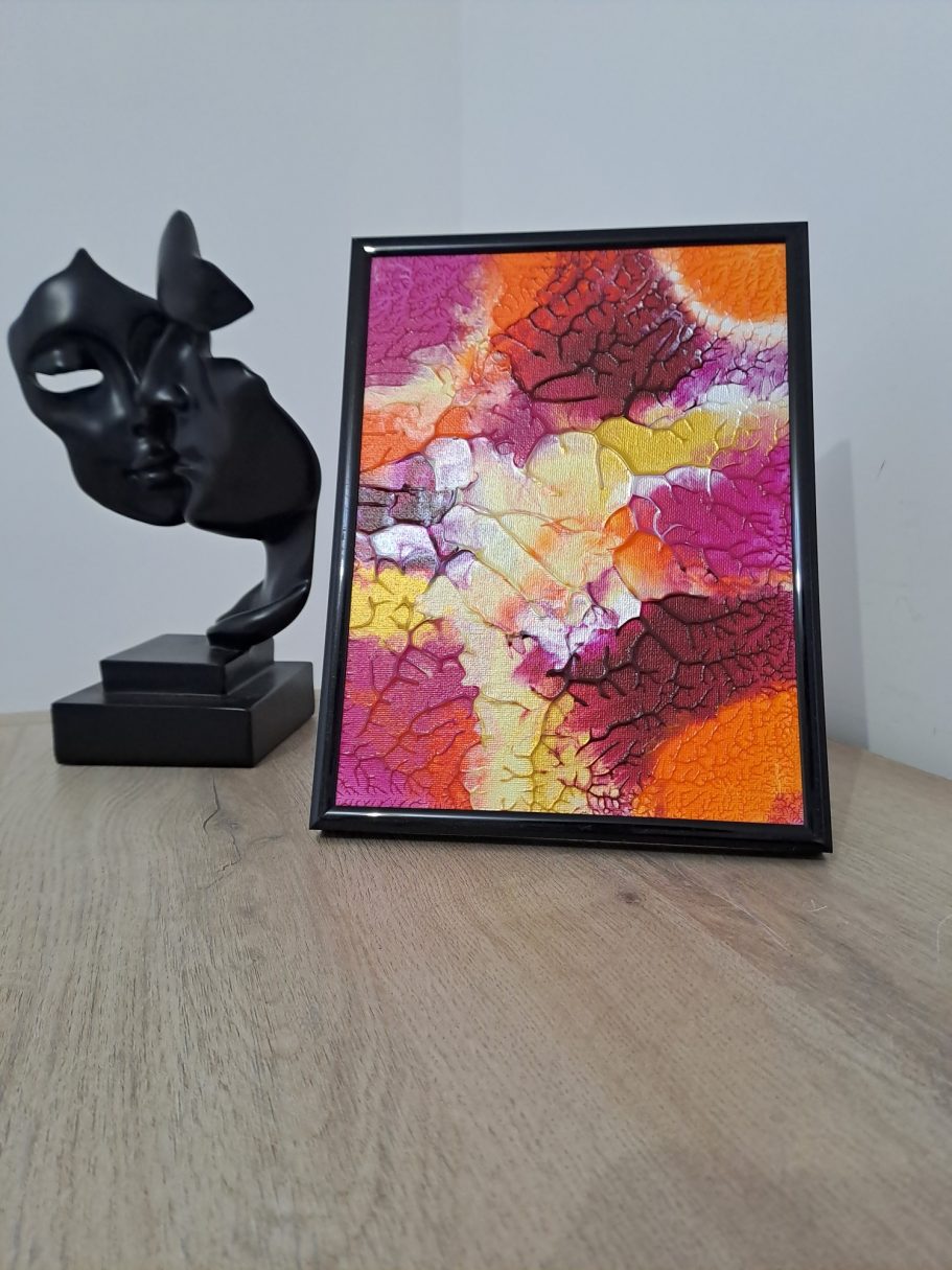 "Aurore tropicale" Une sculpture noire à gauche et un tableau coloré en jaune, rose et orange à droite.